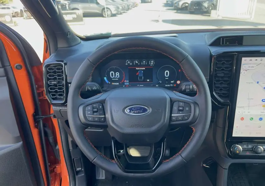 Vue intérieure centrée sur le volant cuir noir avec surpiqûres orange du Ford Ranger Wildtrak 2026 Ignite Orange.