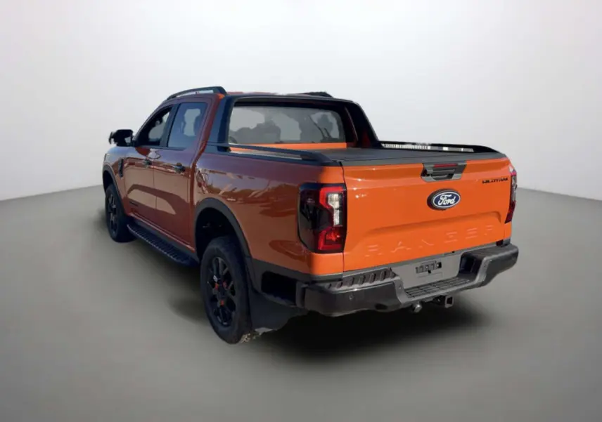 Ford Ranger Wildtrak orange Ignite vu en 3/4 arrière droit, avec benne et jantes noires tout-terrain.