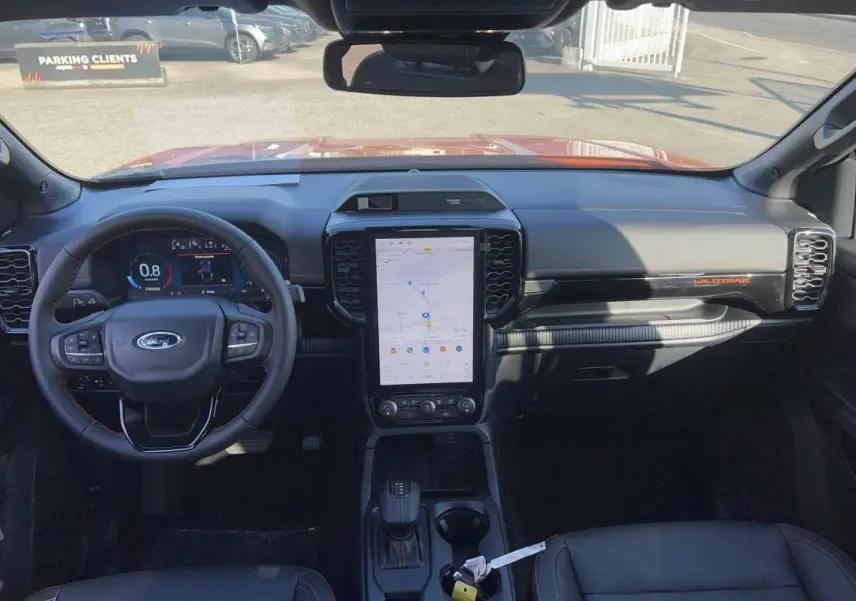 Vue intérieure avant du Ford Ranger Wildtrak Plus 2026 avec tableau de bord noir, écran tactile vertical et volant multifonctions.