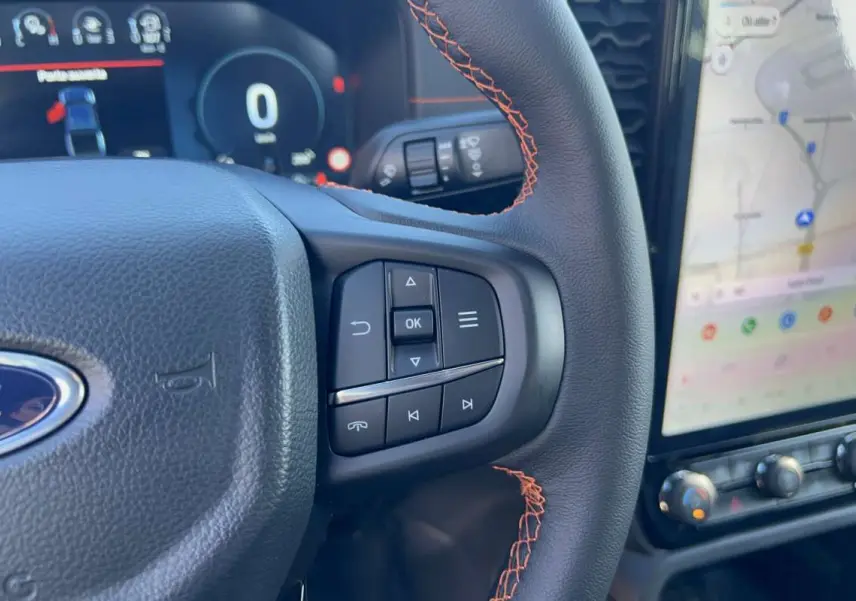 Gros plan sur le volant cuir noir avec surpiqûres orange et commandes multifonctions du Ford Ranger Wildtrak 2026.