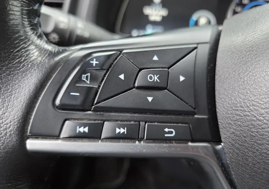 Gros plan sur les commandes multifonctions noires du volant cuir côté gauche du Nissan Leaf II gris foncé 2021.