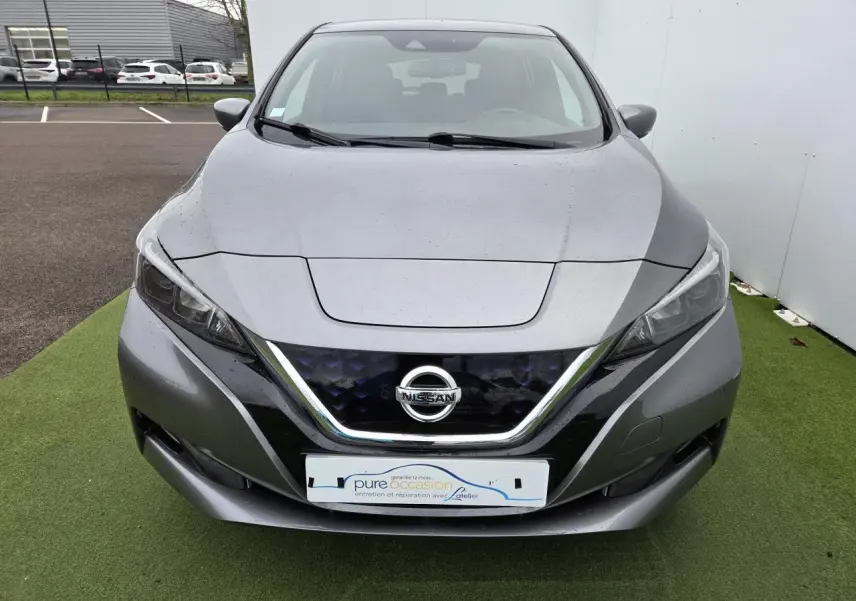 Vue frontale d'une Nissan Leaf II gris foncé métallisé avec calandre noire et logo Nissan bien visible.