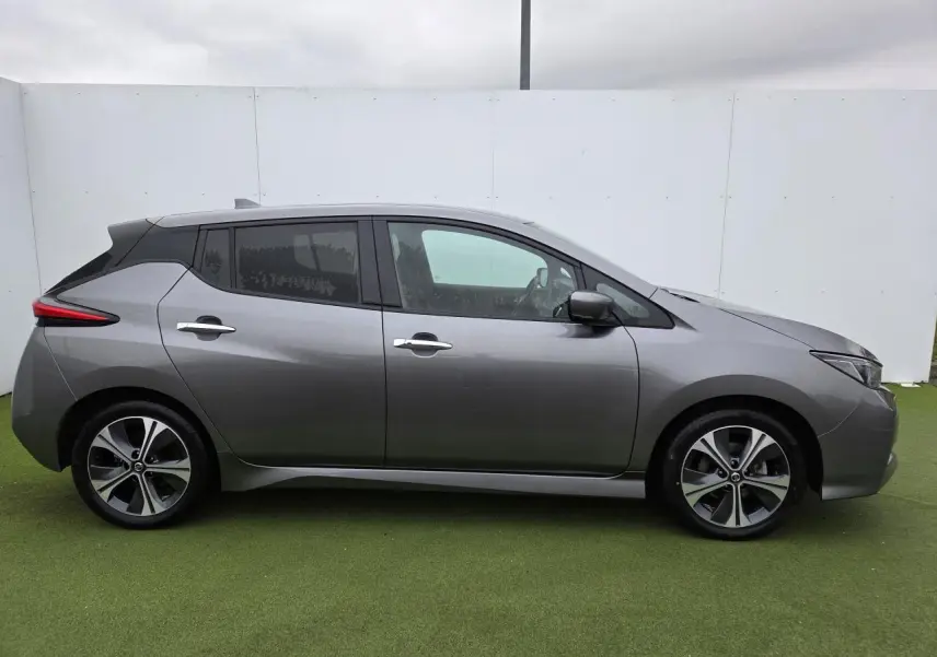 Vue de profil côté gauche d'une Nissan Leaf II gris foncé métallisé avec jantes alliage et vitres teintées.