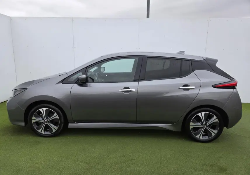 Vue de profil côté gauche d'une Nissan Leaf II gris foncé métallisé avec jantes alliage et vitres teintées.