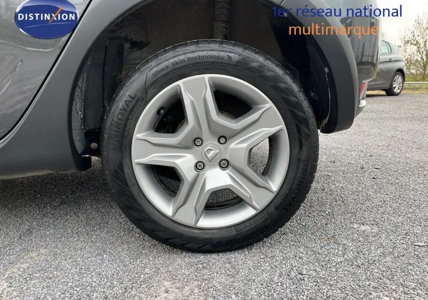 Gros plan sur la roue avant droite d'une Dacia Sandero Stepway gris foncé, avec jante alliage et pneu Uniroyal.