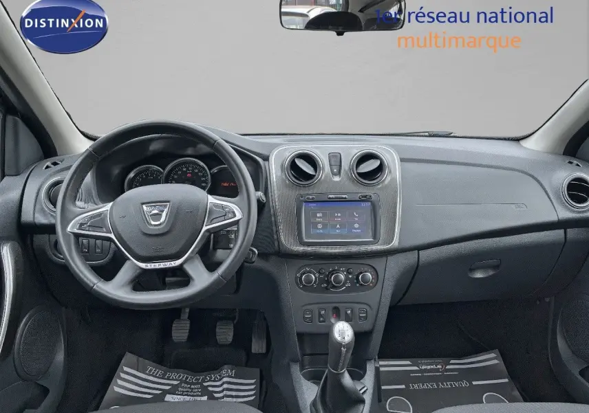 Vue intérieure frontale du tableau de bord gris foncé du Dacia Sandero Stepway 2016 avec volant multifonction et écran central tactile.