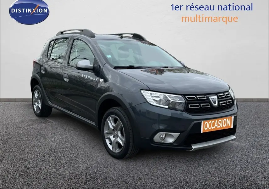 Vue 3/4 avant d'une Dacia Sandero Stepway 0.9 TCe gris foncé avec barres de toit et jantes alliage.