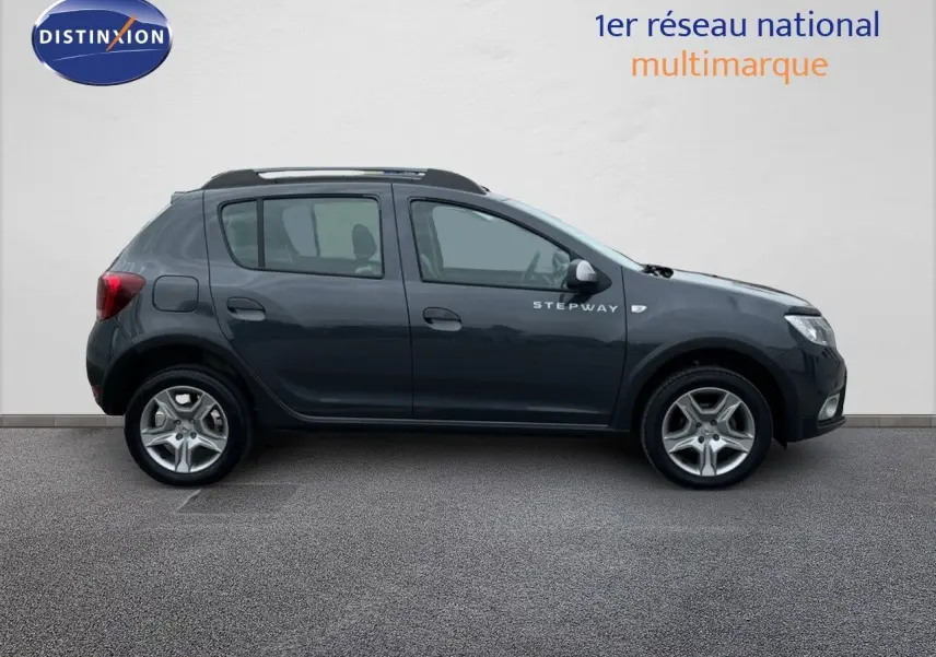 Vue de profil côté gauche d'une Dacia Sandero Stepway gris foncé de 2016 avec jantes alliage et badge Stepway visible.