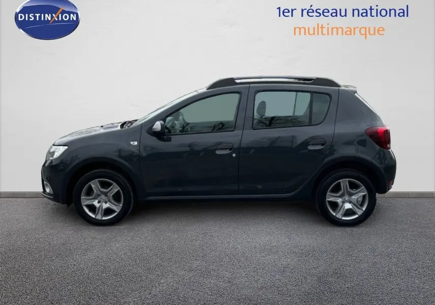 Profil côté gauche d'une Dacia Sandero Stepway 0.9 TCe gris foncé essence de 2016, avec barres de toit visibles.