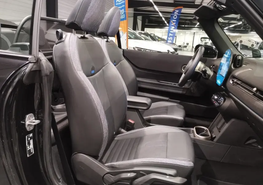 Vue intérieure côté gauche du cabriolet MINI noir, mettant en valeur les sièges sport en similicuir perforé avec accoudoir central.