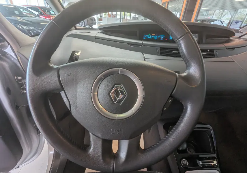 Vue rapprochée du volant en cuir noir et du tableau de bord numérique du Renault Grand Espace IV gris clair de 2012.