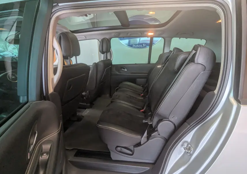 Vue latérale côté droit de l’intérieur gris clair du Renault Grand Espace IV 2012, montrant les sièges noirs en cuir et alcantara.