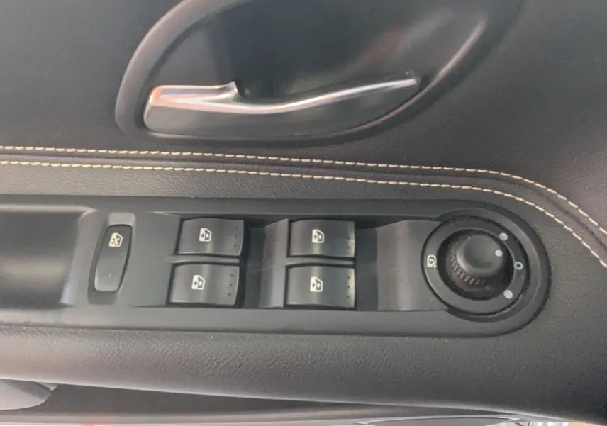 Gros plan sur la commande des vitres électriques et réglage des rétroviseurs sur la porte côté conducteur d’un Renault Grand Espace IV gris clair.