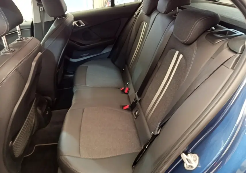 Vue intérieure côté arrière droit de la banquette tissu et cuir gris foncé d’une BMW Série 1 bleu 118i Edition Sport 2023.