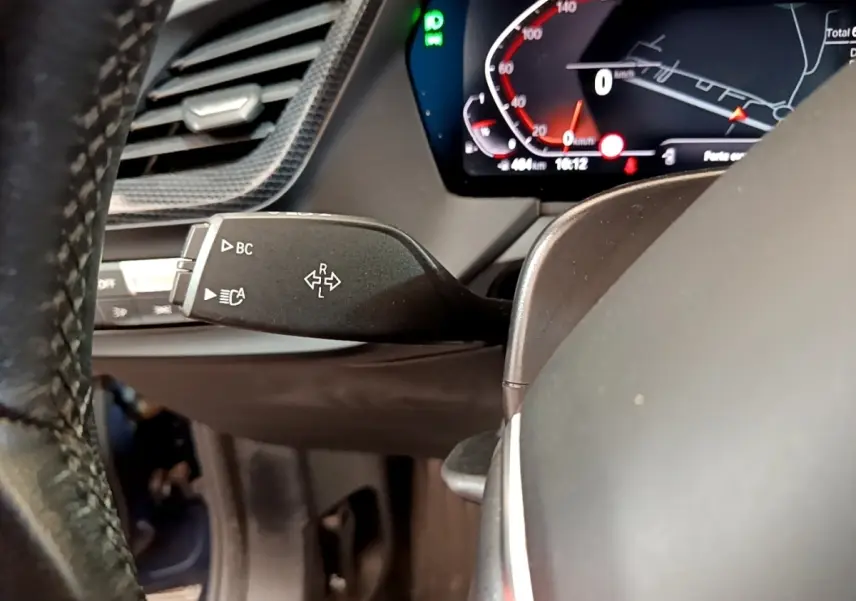 Gros plan sur la commande de clignotants à gauche du volant dans le tableau de bord numérique d'une BMW Série 1 bleue 2023.