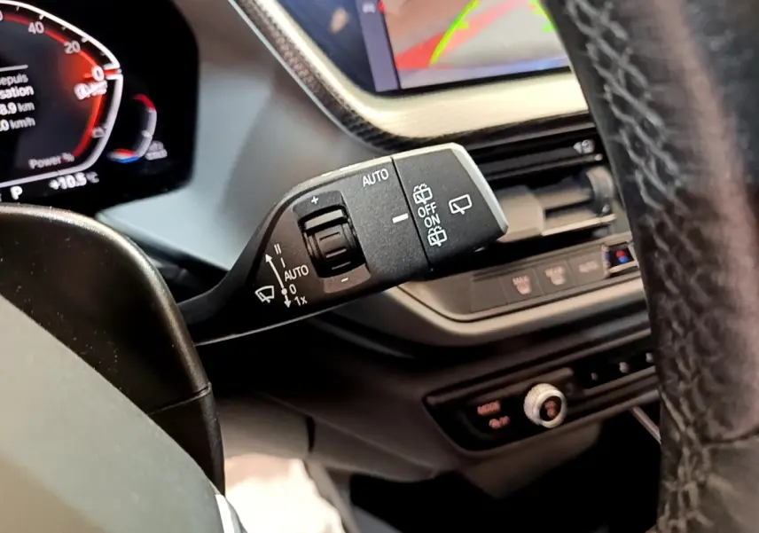 Gros plan sur la commande d’essuie-glace à gauche du volant dans l’habitacle de la BMW Série 1 bleu 118i Edition Sport 2023.
