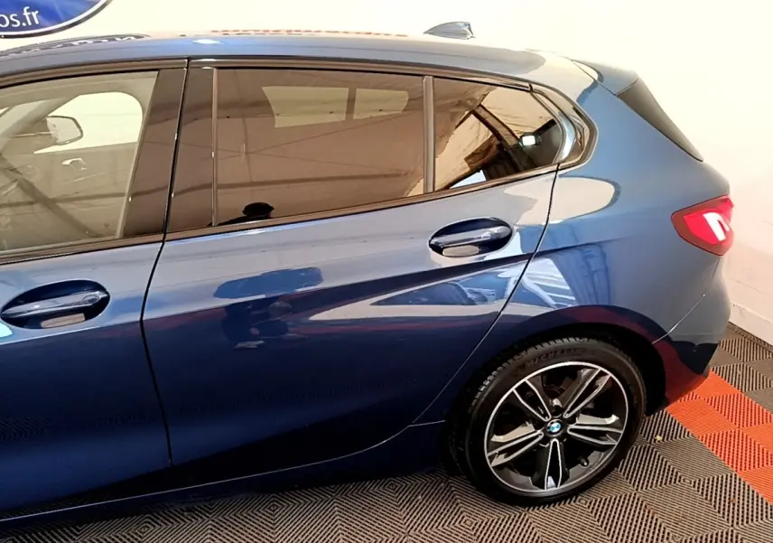 Vue latérale droite sur la partie arrière d’une BMW Série 1 118i Edition Sport bleu avec jante alliage et feux LED allumés.