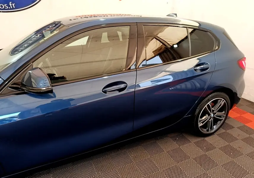 Vue latérale gauche d'une BMW Série 1 118i Edition Sport bleu avec jantes alliage et rétroviseurs ton caisse.