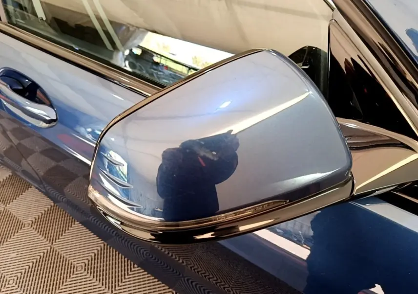 Rétroviseur côté gauche bleu métallisé de la BMW Série 1 118i Edition Sport 2023 avec poignée de porte assortie.