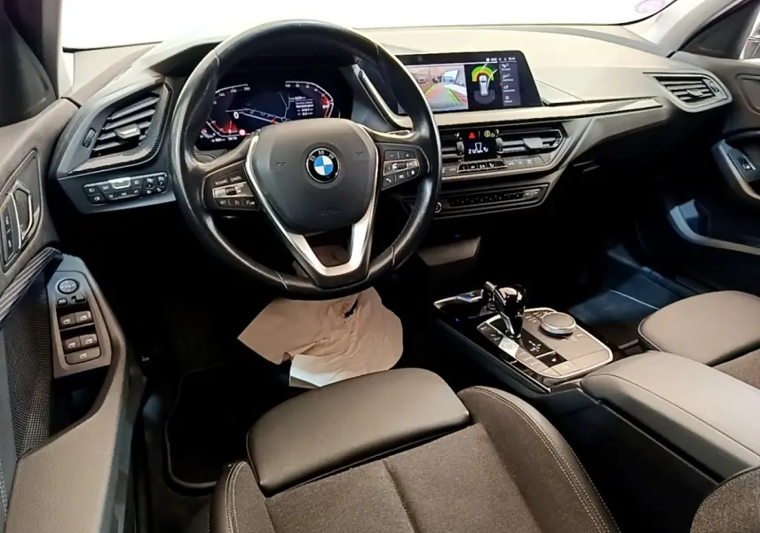 Vue intérieure de la BMW Série 1 118i Edition Sport 2023, tableau de bord et console centrale avec écran tactile couleur.