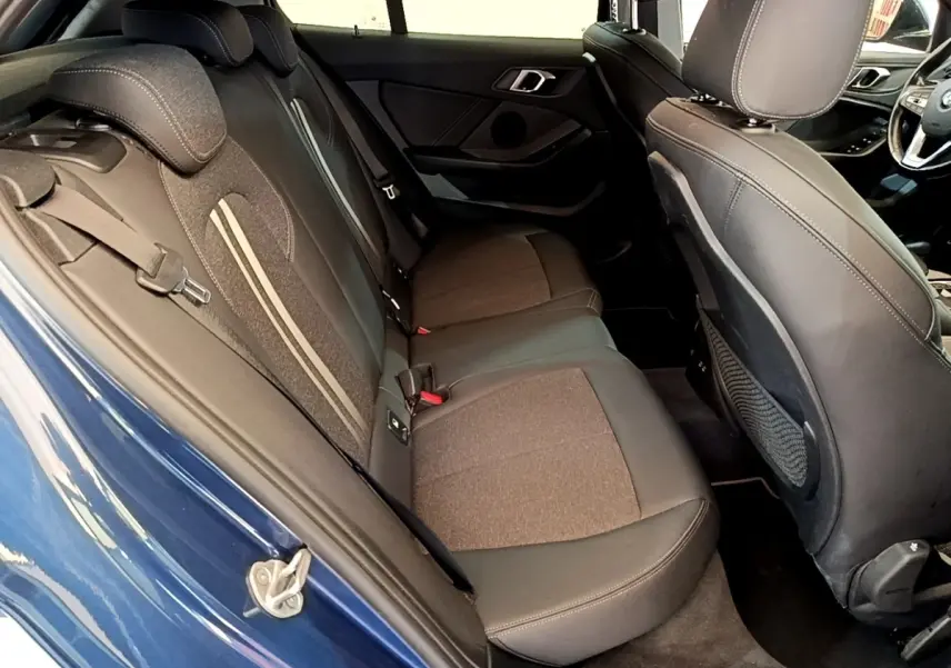 Vue intérieure côté arrière gauche de la BMW Série 1 118i Edition Sport bleu, montrant la banquette arrière et les sièges avant.