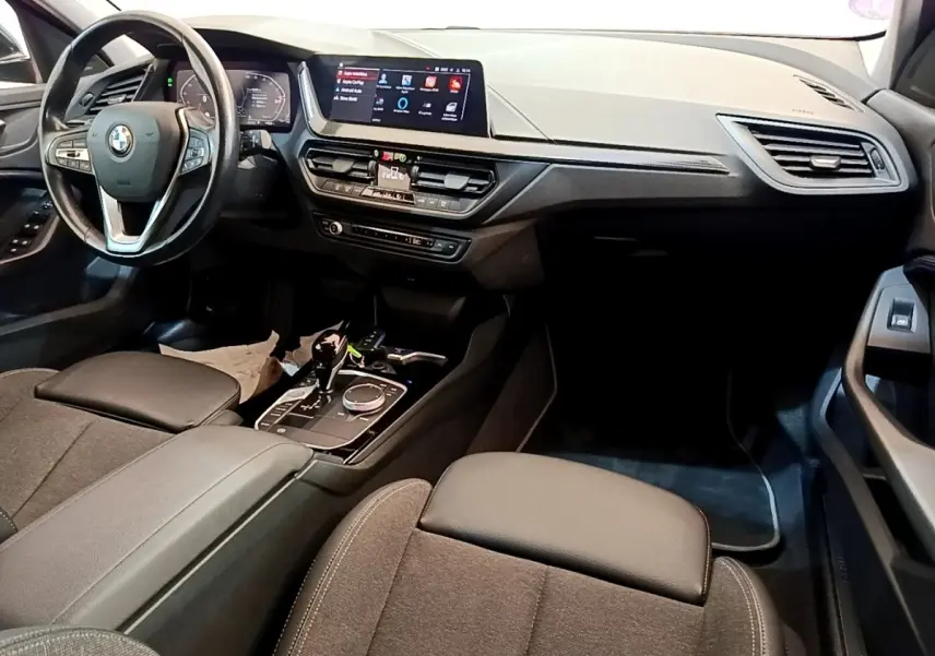 Vue intérieure côté conducteur de la BMW Série 1 118i Edition Sport 2023 avec tableau de bord et écran tactile.