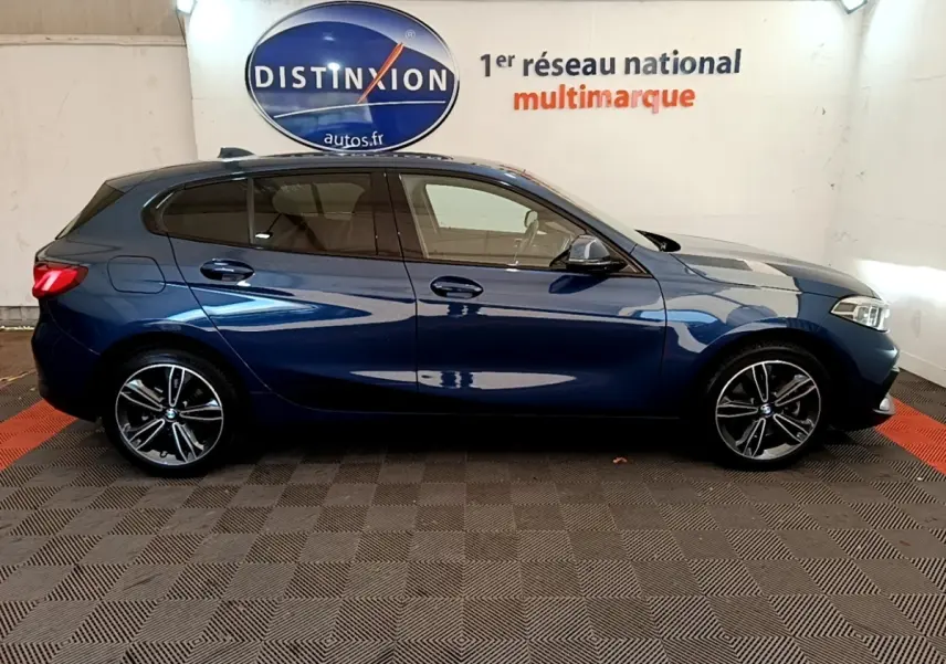 Profil droit d'une BMW Série 1 118i Edition Sport bleu métallisé, avec jantes alliage et vitres teintées.