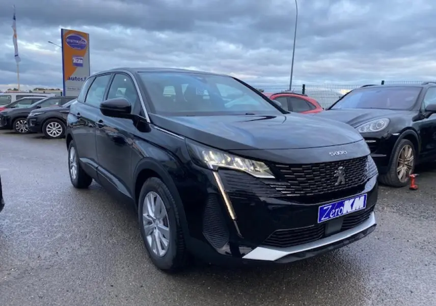 Peugeot 5008 noir vue 3/4 avant droit, avec calandre distinctive et feux LED verticaux allumés.