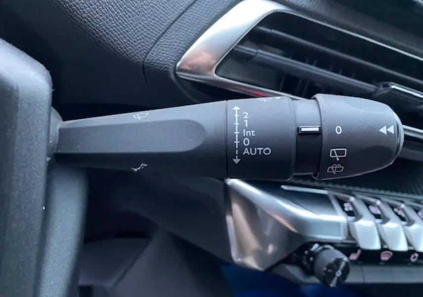 Gros plan sur la commande d’essuie-glace à gauche du volant dans l’habitacle noir du Peugeot 5008 2023.