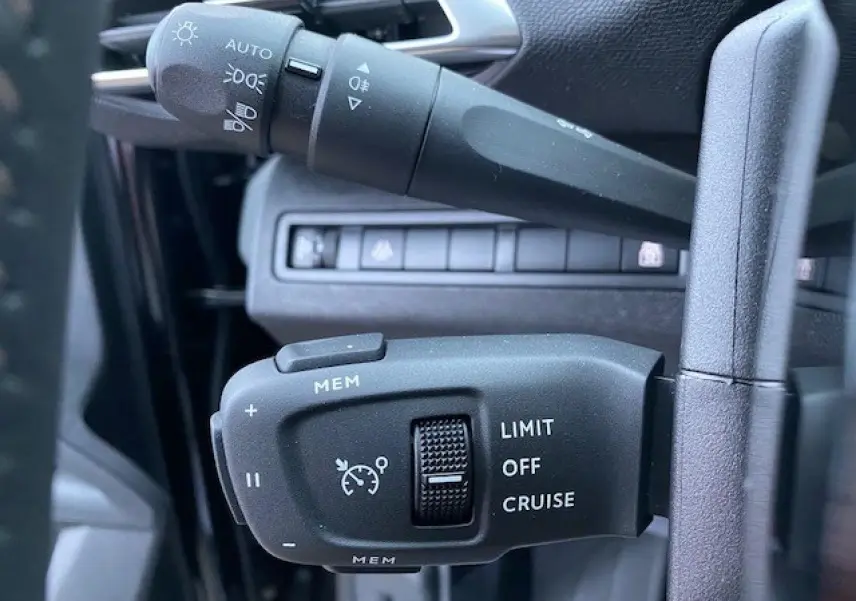 Gros plan sur les commandes du régulateur de vitesse et des feux, intérieur noir du Peugeot 5008 2023.