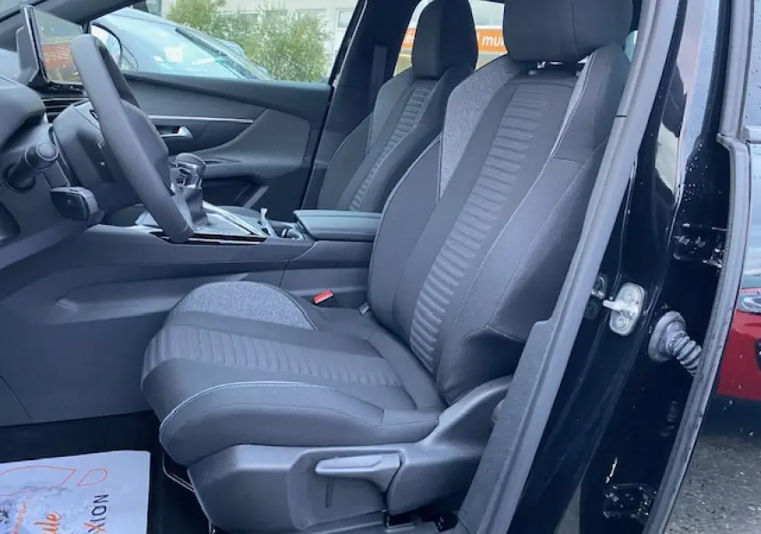 Vue intérieure côté conducteur du Peugeot 5008 noir 2023, mettant en valeur les sièges avant en tissu gris et noir.