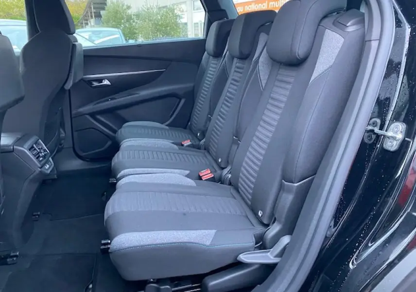Vue latérale intérieure des sièges arrière noirs du Peugeot 5008 2023, avec portes ouvertes et habillage sombre.