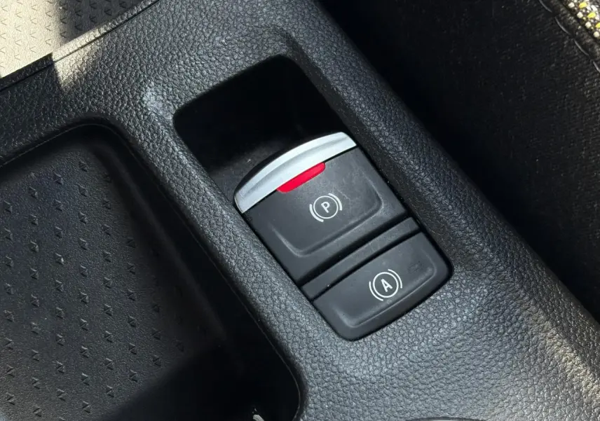 Gros plan sur la console centrale du Renault SYMBIOZ 2025, montrant les boutons de frein de parking électrique et auto-hold.
