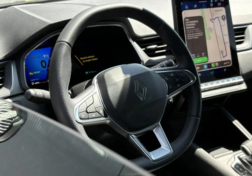 Vue intérieure centrée sur le volant Renault noir avec tableau de bord numérique et écran tactile vertical du Symbioz.