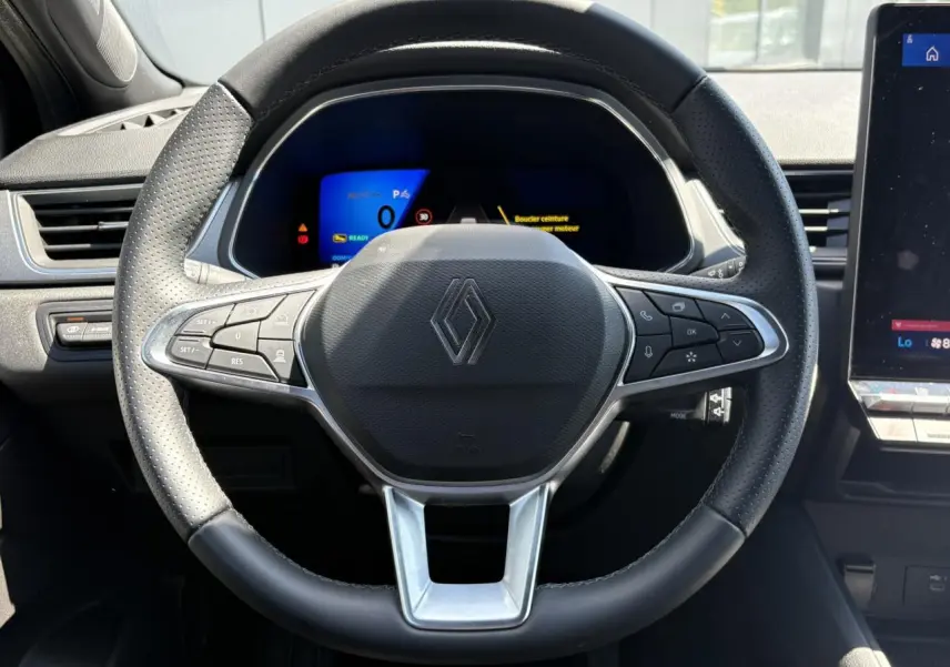 Vue rapprochée du volant noir perforé du Renault Symbioz E-Tech 2025 avec commandes intégrées et tableau de bord numérique.