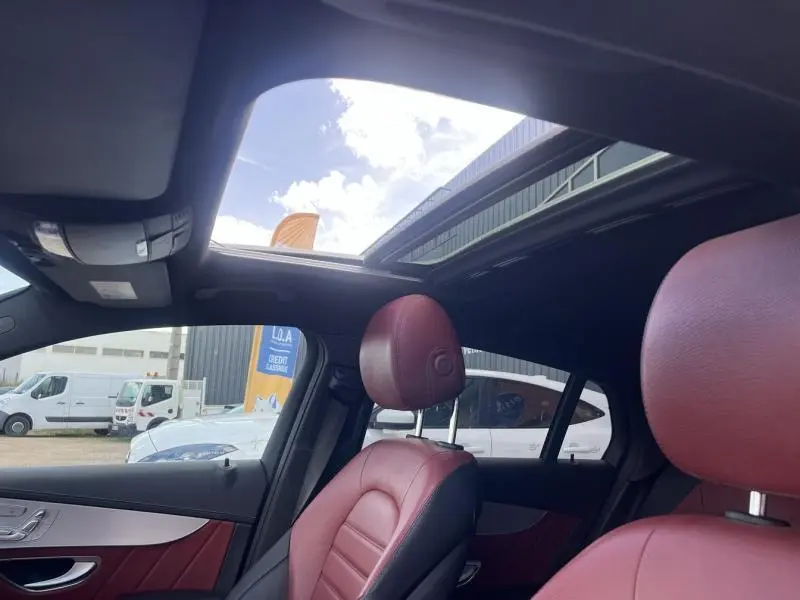 Vue intérieure côté conducteur du Mercedes GLC Coupé blanc avec toit ouvrant et sièges cuir rouge/noir.