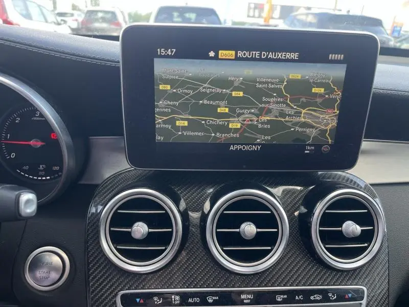 Vue intérieure du tableau de bord de la Mercedes GLC Coupé blanc diamant, avec écran GPS et aérateurs ronds en carbone.