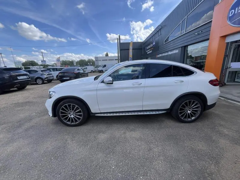 Vue de profil côté gauche d'un Mercedes GLC Coupé blanc diamant brillant avec jantes AMG multibranches bicolores.