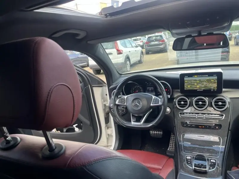 Vue intérieure avant gauche du Mercedes GLC Coupé 220 d avec sièges cuir rouge/noir et tableau de bord carbone.
