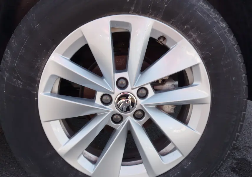 Gros plan sur la jante argentée en alliage du Skoda Kamiq 2024 avec logo au centre, entourée d’un pneu noir.