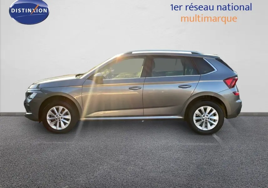 Profil côté gauche d'un Skoda Kamiq gris graphite métallisé 2024 garé devant un mur blanc.