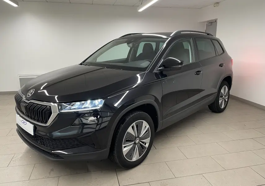 SUV Skoda Karoq noir Magic nacré vu en 3/4 avant droit, avec phares allumés et jantes spécifiques Pack Techno.