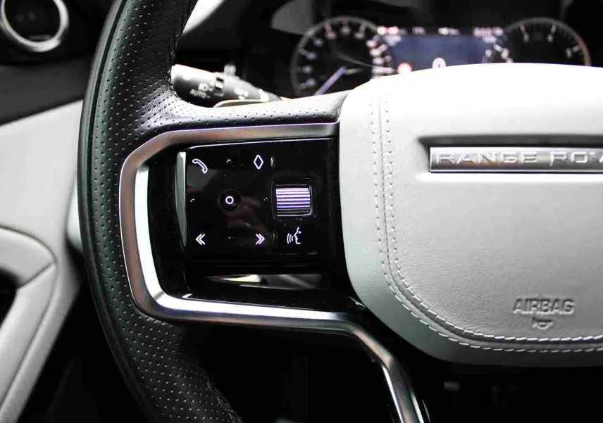 Gros plan sur le volant gris clair du Range Rover Evoque 2023 avec commandes tactiles intégrées.