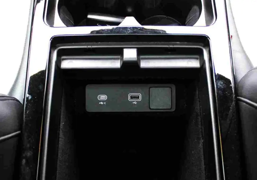 Gros plan intérieur sur la console centrale noire du Range Rover Evoque 2023, montrant prises USB et porte-gobelets.