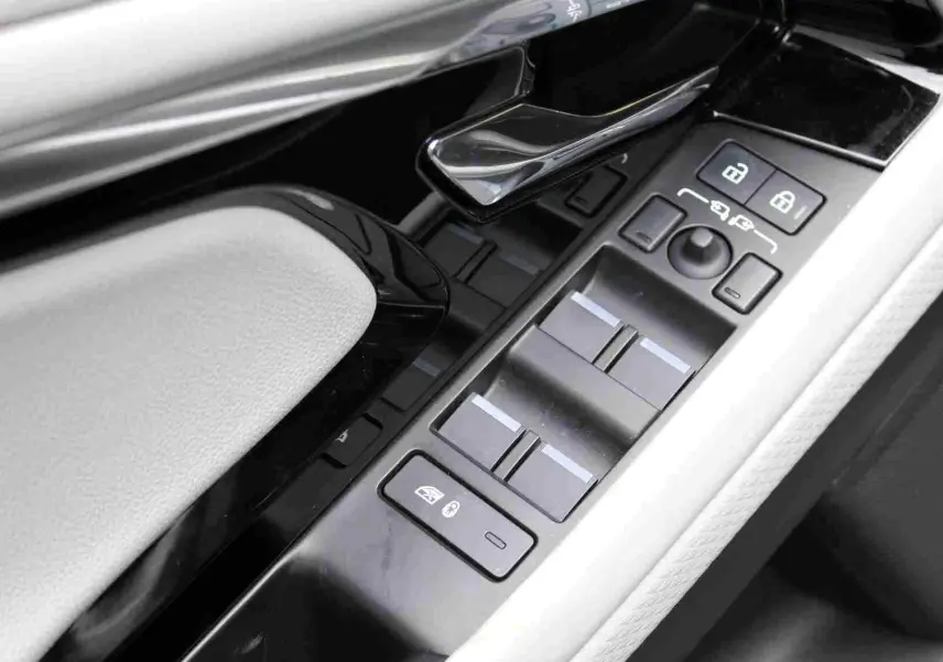 Gros plan sur la commande des vitres et rétroviseurs côté conducteur du Range Rover Evoque gris métal 2023 hybride rechargeable.