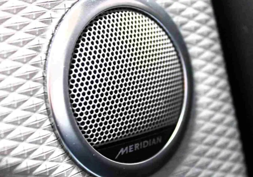 Gros plan sur l'enceinte audio Meridian intégrée dans l'habitacle du Range Rover Evoque 2023 gris métal.