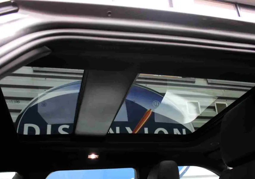 Toit panoramique ouvert du Range Rover Evoque gris métal 2023, vue intérieure arrière avec sièges en cuir noir.