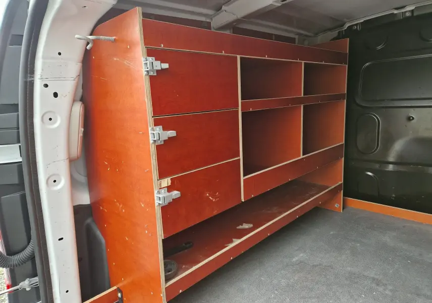 Vue intérieure du coffre arrière d'un Renault Kangoo blanc 2019, avec étagères en bois installées côté gauche.