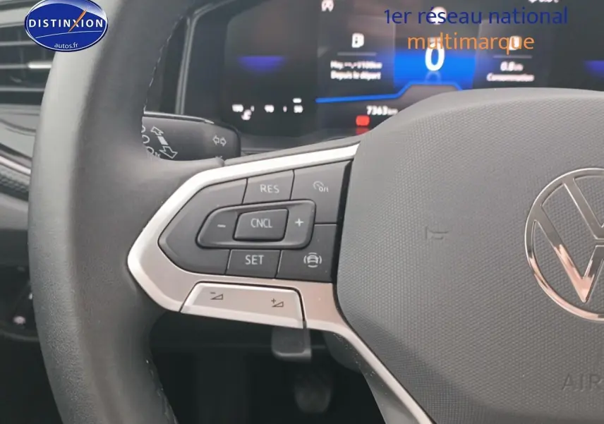 Gros plan sur le volant multifonction noir avec commandes de régulateur de vitesse de la Volkswagen Polo blanche.