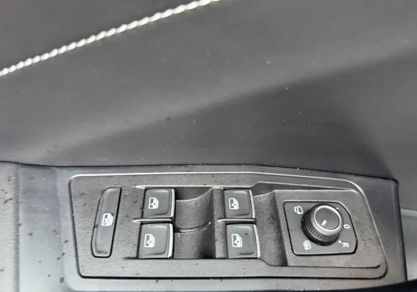 Gros plan sur les commandes des vitres électriques et rétroviseurs côté conducteur d’un Volkswagen T-Roc blanc toit noir.